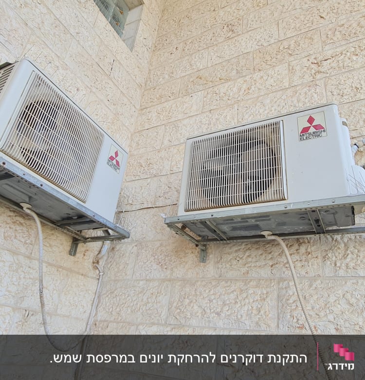 שני מזגנים מותקנים על קיר אבן עם דוקרנים להרחקת יונים